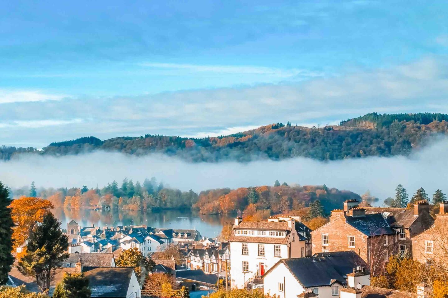 Aerial top view over Bowness On Windermere on an early morning with fog and mist rising on lake Windermere. Autumn in the Lake District, Cumbria, UK.